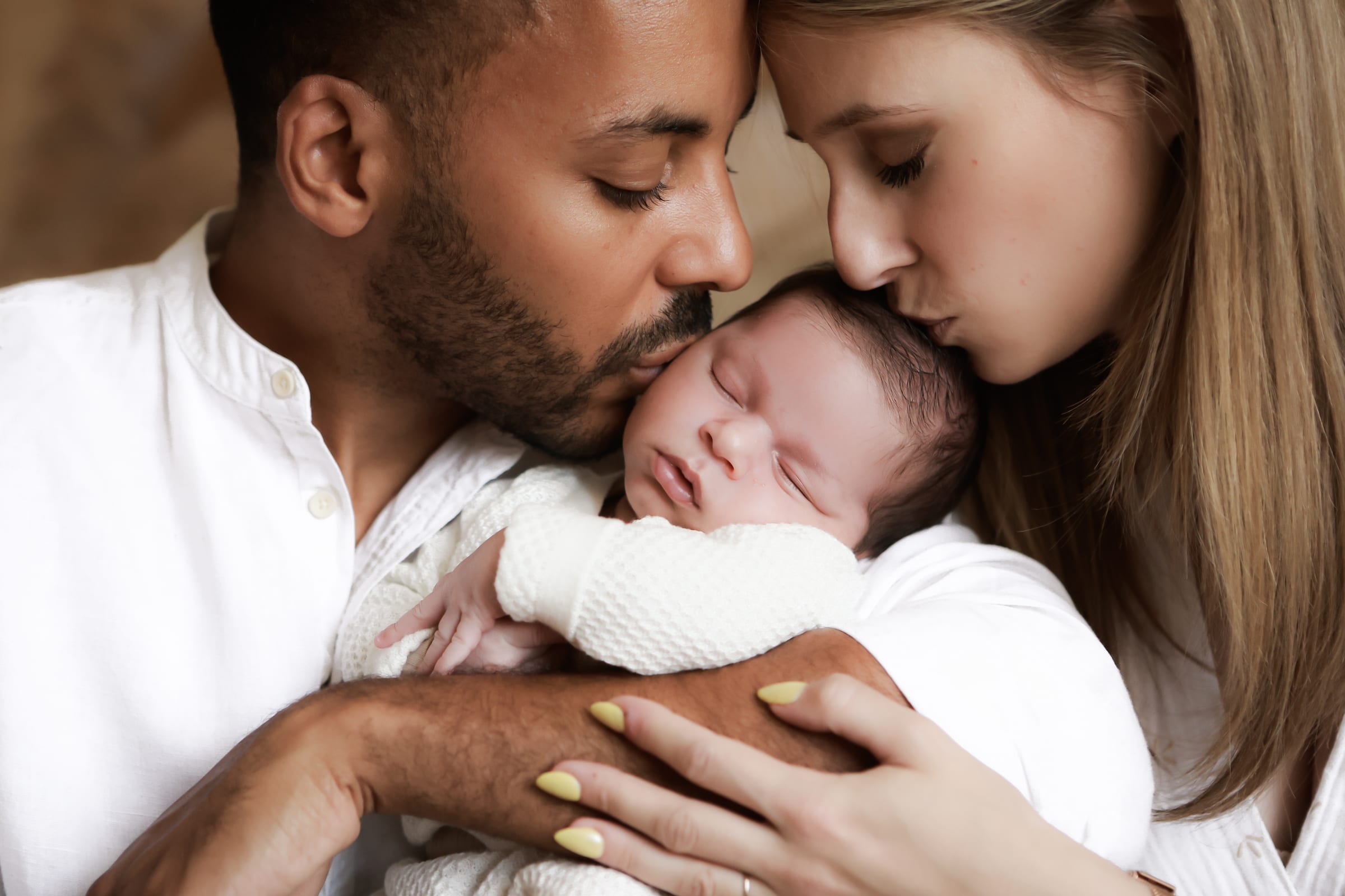 Deux jeunes parents embrassent tendrement leur nouveau-né